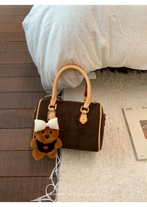 Close-up of retro brown frosted cylindrical handbag with cute bear charm on white faux fur rug
