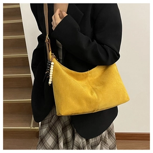 Détail du sac cabas en daim jaune avec bandoulière en cuir marron et breloque perlée