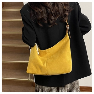Détail d'un grand sac hobo en daim jaune avec sangle réglable et bijou de sac