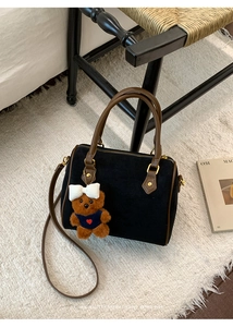 Detail of black frosted Boston bag with brown handles and cute plush bear charm