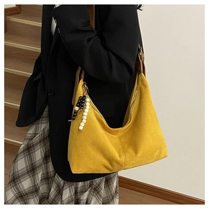 Detail of yellow suede hobo bag with wooden bead tassel and brown leather strap
