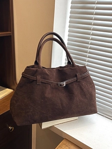 Bolso tote grande de ante marrón con hebilla en un alféizar de ventana soleado