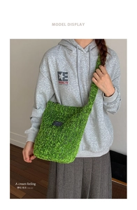 Detail der grasgrünen Plüsch-Beuteltasche mit schwarzem Mode-Etikett und breitem Riemen