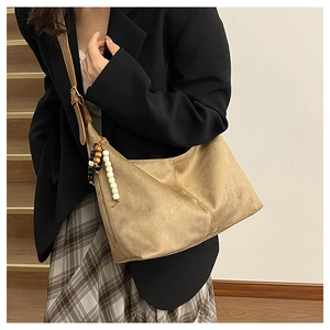 Détail du sac cabas en daim kaki avec glands en perles de bois colorées et sangle en cuir