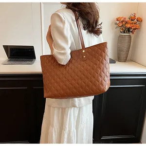 Detailed view of brown quilted tote bag with long shoulder straps and gold rivet accents