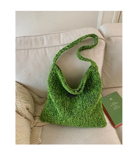 Detail van de groene wollen hobo tas textuur met een zwarte patch op een beige bank