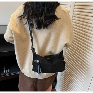 Model wearing black nylon crossbody bag with adjustable strap and metal eyelet details