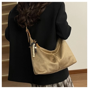 Détail du sac hobo en daim avec gland en perles bohème et bandoulière en cuir lisse
