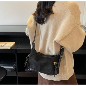Detail of black suede shoulder bag with long leather zipper pull and slim strap