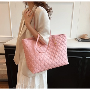 Detail of light pink tote bag featuring diamond quilt texture and gold studs