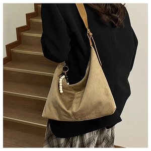 Close-up of olive suede tote bag showing soft texture and beaded keychain detail
