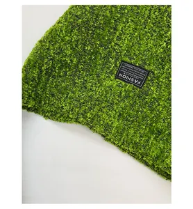 Detailopname van groene boucle wol textuur met Fashion Instinct geweven label op de tas