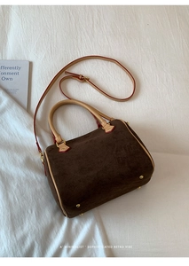 Detailed view of dark brown suede pillow bag with cream leather straps and gold feet