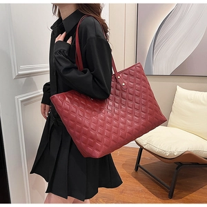 Detail of burgundy quilted tote bag with gold rivet hardware and premium leather texture