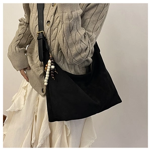 Detail view of black suede hobo bag featuring vintage wooden beads and wide strap