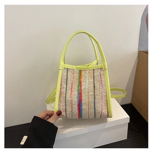Detalle de rayas tejidas de colores y asa de cuero verde neón en un mini bolso tote