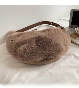 Detail of coffee brown faux fur shoulder bag with leather strap on a white bed sheet