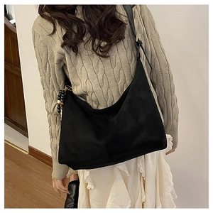 Détail d'un grand sac fourre-tout en daim noir avec bandoulière et ornement de perles