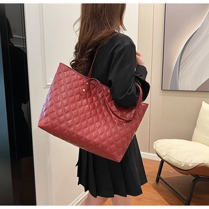 Deep red quilted tote bag with large capacity shown on model in a modern interior