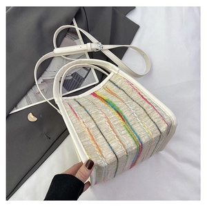Primer plano de la textura tejida con rayas de colores y el asa de cuero blanco del bolso