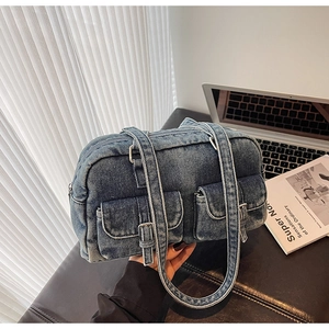 Close-up of vintage denim underarm bag with metal buckles on office desk setup