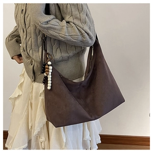 Detail of retro faux suede brown tote bag featuring a decorative wooden bead tassel charm