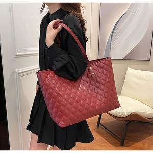 Close-up of burgundy quilted tote bag featuring golden rivets and premium faux leather finish