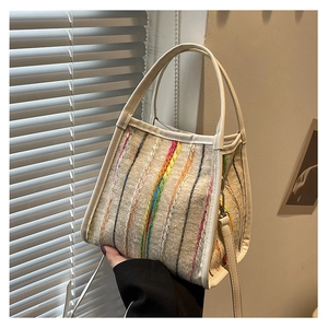 Detalle de las rayas tejidas coloridas en un bolso cubo de tweed gris con asa de cuero