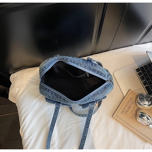 Internal view of blue denim tote bag showing black lining and zip pocket with lifestyle props