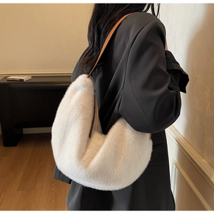Detail of white plush faux fur hobo bag with brown leather strap on model shoulder