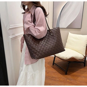 Detail of dark brown quilted tote bag with gold rivet accents on shoulder straps