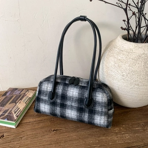 Detailed close-up of a classic black and white plaid tote bag on a rustic wooden table