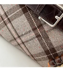 Macro view of plaid fabric texture and dark brown crocodile-embossed leather strap