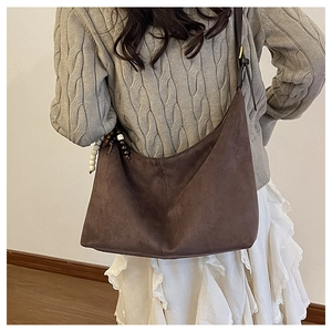 Sac fourre-tout en daim marron porté par un mannequin avec pendentif perlé bohème