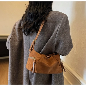 Detail of caramel suede bag featuring long tassels and gold metal hardware accents