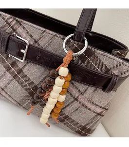 Detailed view of retro wooden bead charm with brown, beige and yellow beads on bag