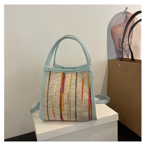 Detalle del bolso de cubo tejido de colores con adornos y asa de cuero azul claro