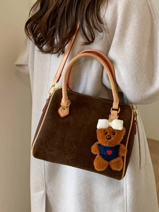 Brown frosted Boston pillow bag with cute bear charm worn by a model in an autumn coat