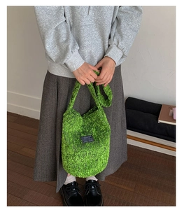Detail der weichen grünen Plüsch-Beuteltasche mit Fashion-Aufnäher, präsentiert von Modell