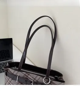 Close-up of comfortable leather straps and metal hardware on plaid tote bag