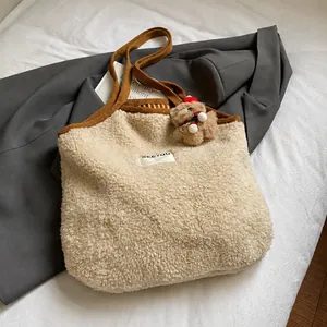 Detail einer Plüsch-Tragetasche mit Bärenanhänger auf grauem Blazer im Lifestyle-Stil