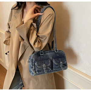 Detailed view of vintage denim shoulder bag with metal buckles and utility pockets