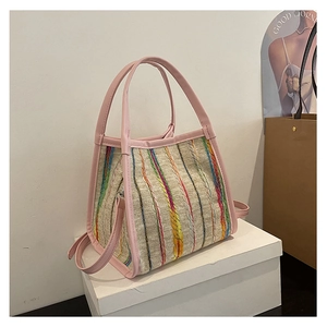 Detalle de bolso tejido colorido con ribete de cuero rosa y asa en soporte de exhibición