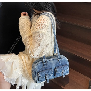 Close-up of vintage blue denim shoulder bag with decorative buckle pockets and long strap