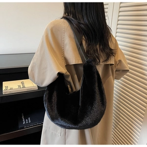Close-up of black faux fur shoulder bag texture with glossy long plush and leather strap
