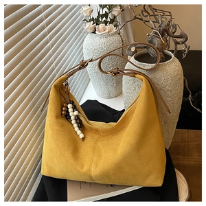 Détail macro du sac cabas en daim gingembre avec bandoulière en cuir et pendentif en perles