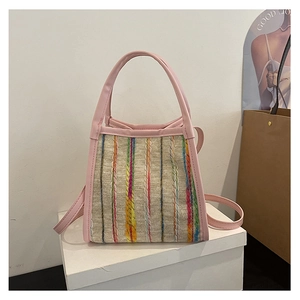 Detalle de asas de cuero rosa y rayas tejidas de colores en el bolso tipo cubo