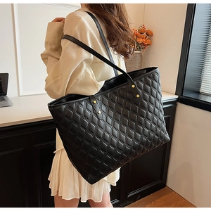 Detailed macro view of black quilted faux leather tote with elegant golden hardware rivets