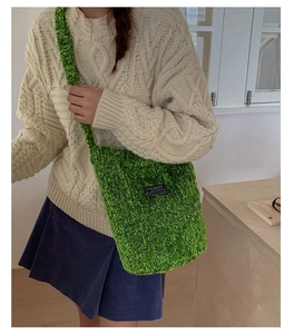 Detailansicht der grasgrünen Strick-Eimertasche mit einem schwarzen Modeetikett vorne