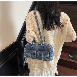 Detail view of a vintage washed blue denim shoulder bag with two front flap pockets